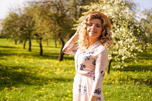 Smiling summer woman with straw hat in park - apple garden in spring sunny day