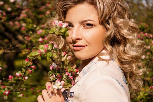 Romantic young woman in the spring garden among apple blossom. Beautiful woman, happy spring