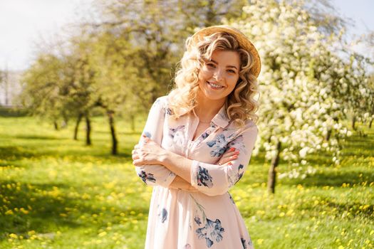 Smiling summer woman with straw hat in park - apple garden in spring sunny day