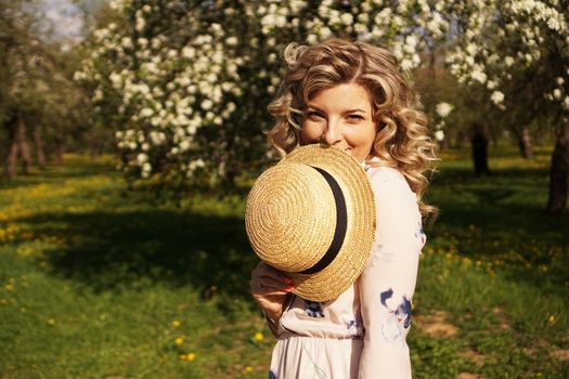 Woman covered half the face with a straw hat - happy time in the green garden - spring and summer time