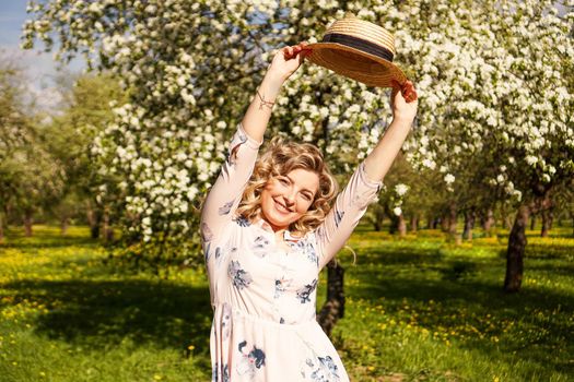 Smiling summer woman with straw hat in park - apple garden in spring sunny day