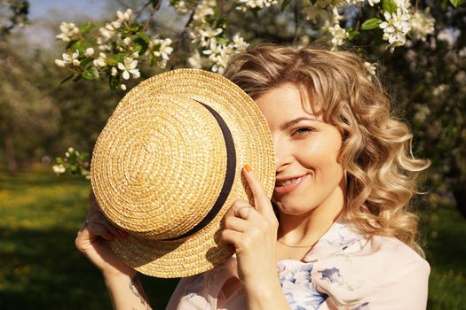 Woman covered half the face with a straw hat - happy time in the green garden - spring and summer time