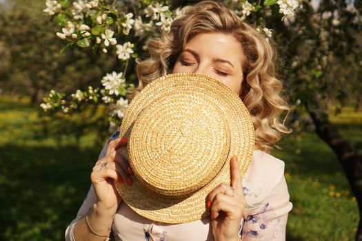 Woman covered half the face with a straw hat - happy time in the green garden - spring and summer time