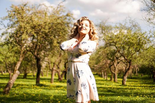 Beautiful young woman in apple garden in spring sunny day - happy moments