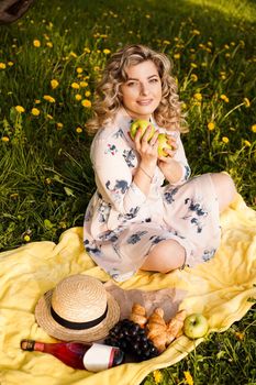 Beautiful blond woman - happy lifestyle, weekend out for a walk in a picnic park in the summer garden, model sits on plaid with food -summer weather