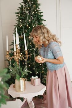 Attractive young woman smiling while holding a candle celebrating Christmas. New Year - cozy interior