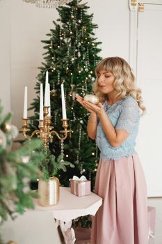 Attractive young woman smiling while holding a candle celebrating Christmas. New Year - cozy interior