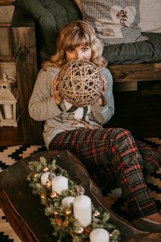 Young beautiful woman in pajamas near decorative fireplace. Christmas mood, New year