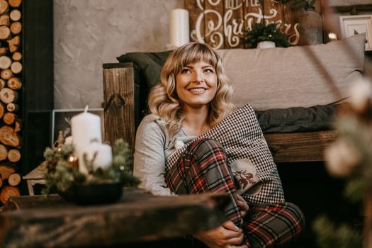 Young beautiful woman in pajamas near decorative fireplace. Christmas mood, New year