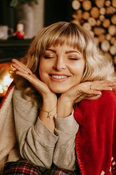 Close up portrait of beautiful young girl with long curly hair on a christmas background with lights. Magic warm new year photo. Cozy interior.