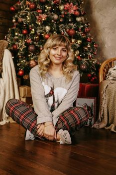 Cheerful smiling blonde woman decorates Christmas tree with balls. Christmas time. Happy holiday. Xmas tree. New Year surprise present