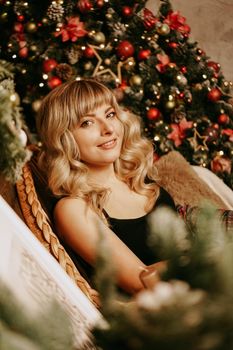 Close up portrait of beautiful young girl with long curly hair on a christmas background with lights. Magic warm new year photo. Cozy interior.