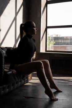 Beautiful sexy woman on leather sofa in dark room