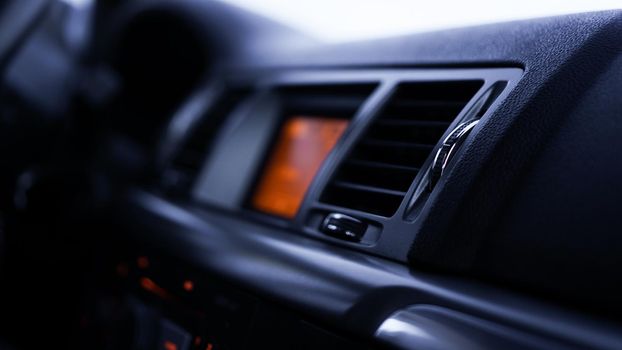 Buttons of radio, dashboard, climate control in car close up - black and orange