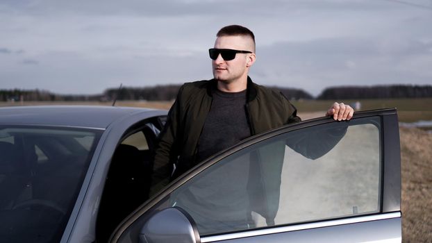 Handsome man in sunglasses near the car. Luxury life.