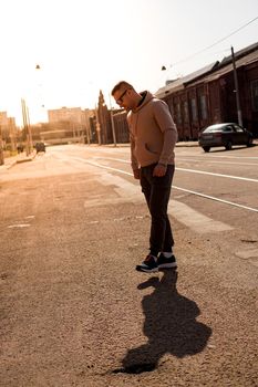 Hipster walking in the street with red brick wall building in summer day. Young man in full growth. Lifestyle photo