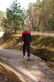 Young male athlete running in forest. Man jogging in the morning in the forest or park
