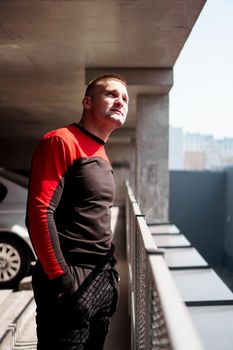 Young man in sports uniform in the parking lot. City view on a sunny day