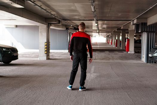 A young man in a sports uniform in an underground parking lot. Back view