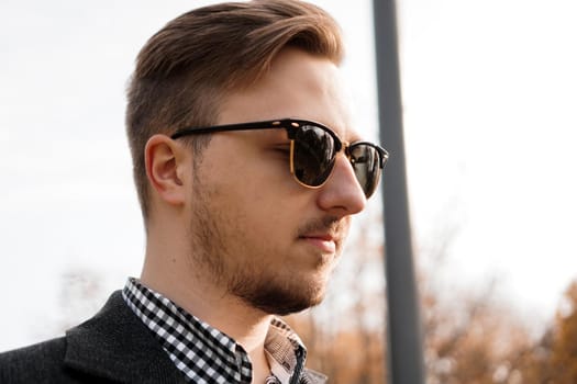 Outdoors portrait of fashionable young man with sunglasses