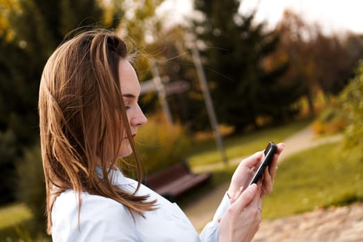 Woman using mobile smart phone in the park.