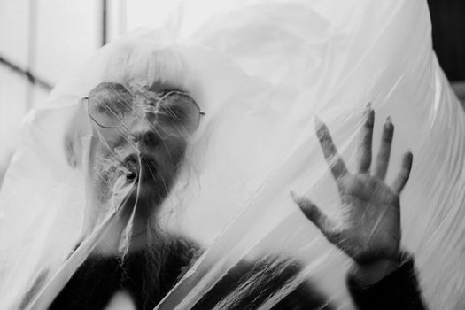 Ecology concept. Girl with plastic wrap Hand raised. City Style. Urban photo. Black and white