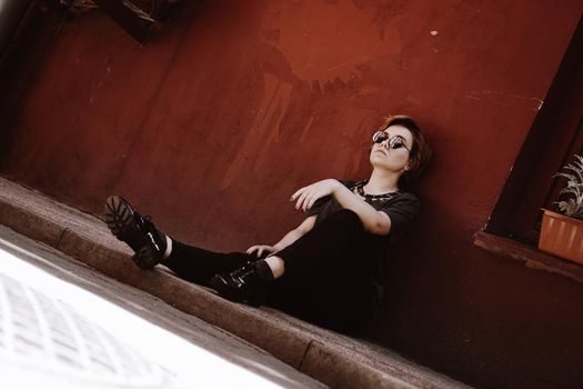 Portrait of a beautiful woman in sunglasses sitting on the floor over red wall