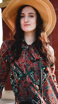 Portrait of pretty woman wearing dress and straw hat in sunny warm weather day. Walking at summer park.