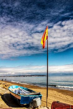 Fishing boats on the shore under spanish flag in the morning