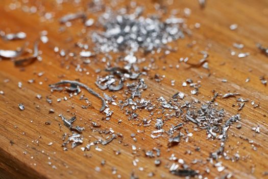 Small metal chips on a wooden background close up