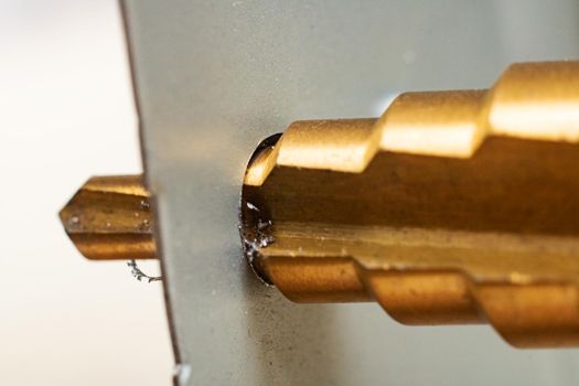 Multistage drill in sheet metal close up, macro photo