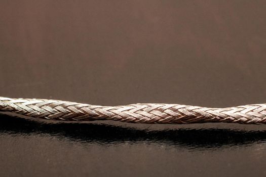 Metal shielded wire on black background close up, macro photo