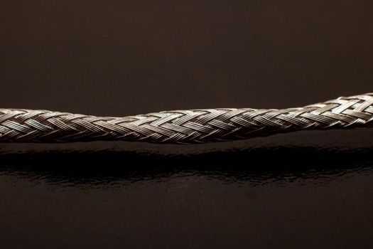 Metal shielded wire on black background close up, macro photo