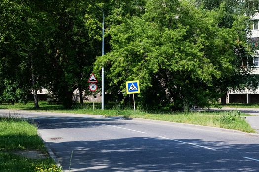 Sign of the pedestrian crossing on the road among the green forest in summer, landscape
