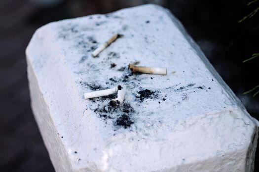 Cigarette butts lie on the concrete surface close up, environmental pollution