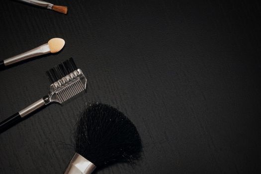 A set of brushes for applying makeup close-up on a dark background, copy space