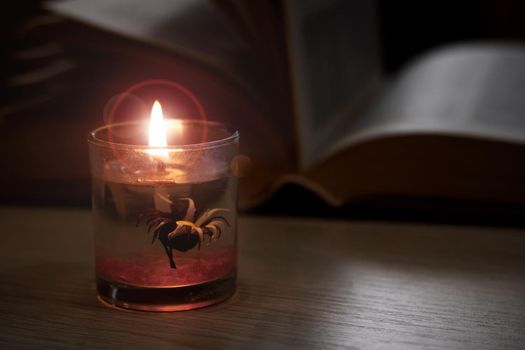 Bright candle in the dark against the background of the book close up, copy space