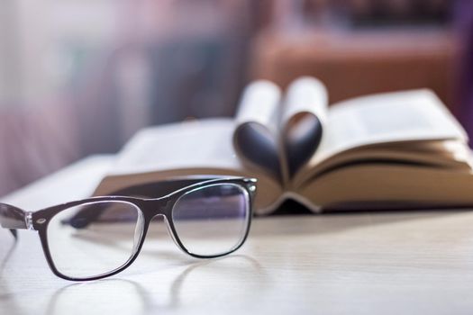 Black glasses on the background of the book in the light of the sun close up, copy space