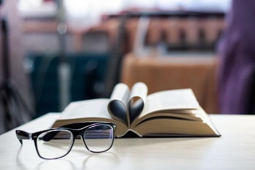 Black glasses on the background of the book in the light of the sun close up, copy space