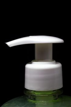Dispenser and green liquid soap closeup, isolated on black background