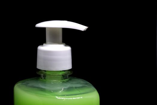 Dispenser and green liquid soap closeup, isolated on black background