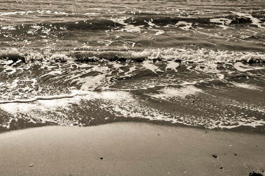 Waves, light and sand texture on the beach in the morning