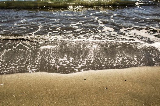 Waves, light and sand texture on the beach in the morning