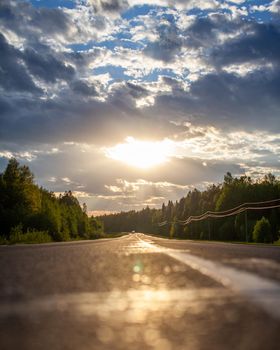 Country road with markings in the middle of the forest. Path and forward movement in the sun. Beautiful, green forest in the spring at sunset. Concept for success in the future goal and passing time