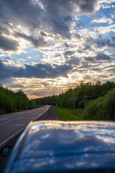 Country road with markings in the middle of the forest. Path and forward movement in the sun. Beautiful, green forest in the spring at sunset. Concept for success in the future goal and passing time