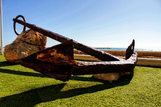 Santa Pola, Spain- February 16, 2018: Old anchor on a promenade of Santa Pola, Alicante. Mediterranean sea on background.