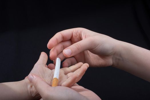 Hand is giving out cigarette on a black background