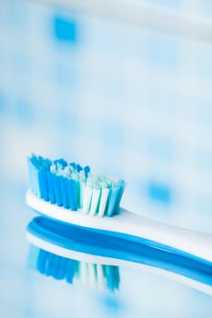 toothbrush on blue tile background with mirror reflection