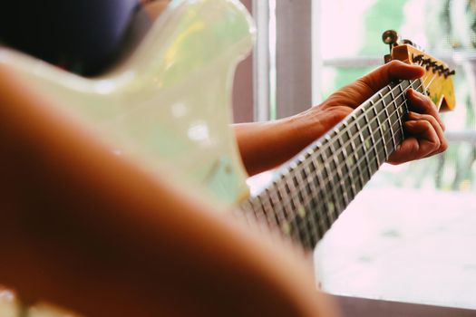 Woman hands playing electric guitar close up