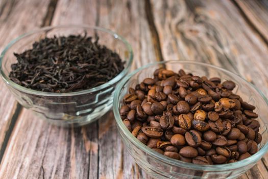 Roasted coffee grains in a bowl and custard tea leaves in the background. Natural ingredients for making drinks and desserts